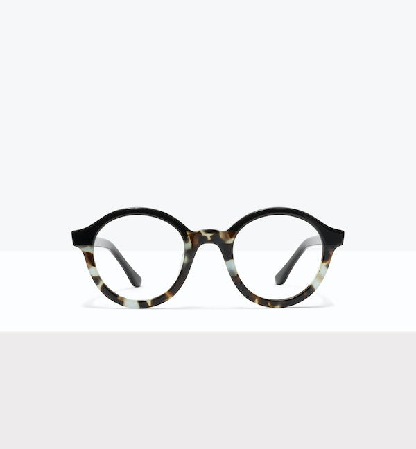 Round brown eyeglasses on a concrete ledge with a blurred background.